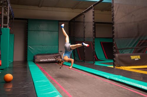 Enfant réalisant une figure acrobatique sur trampoline dans un couloir de saut