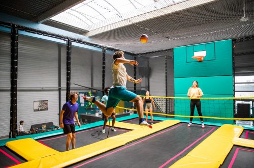 Jeunes en train de jouer au volley sur trampoline, en plein saut au-dessus du filet